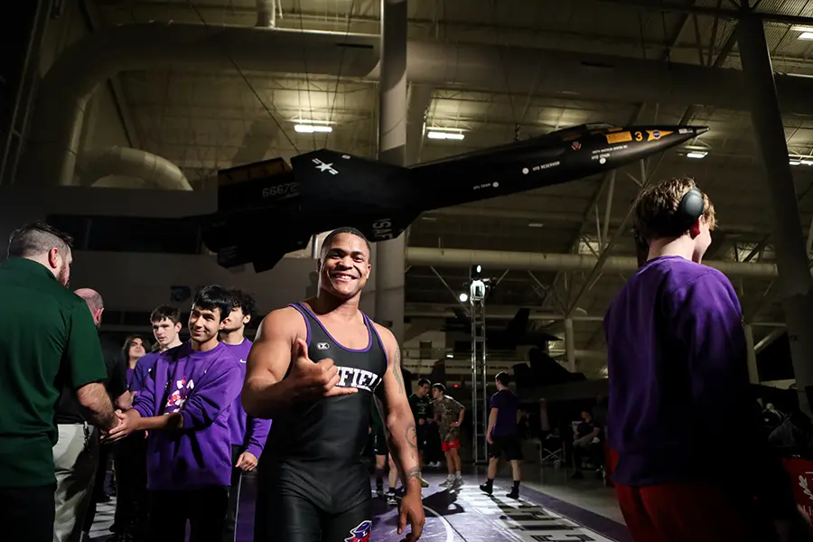 Divenson posing under an airplane at a wrestling event at Evergreen Museum.