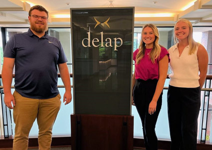 Nick Severson '24, Sophia vanderSommen ’25 and  Caitlin Hillman ’24 next to a Delap sign.