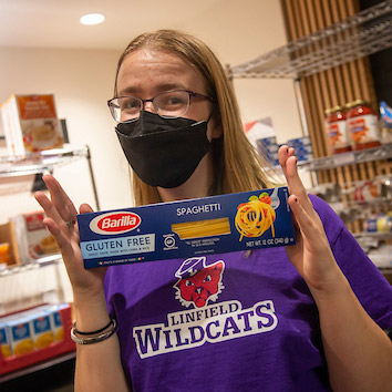 Isabella holding a box of spaghetti available for students in the food pantry