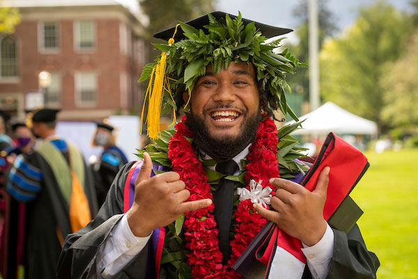 Male student in cap, gown and cords at Commencement.