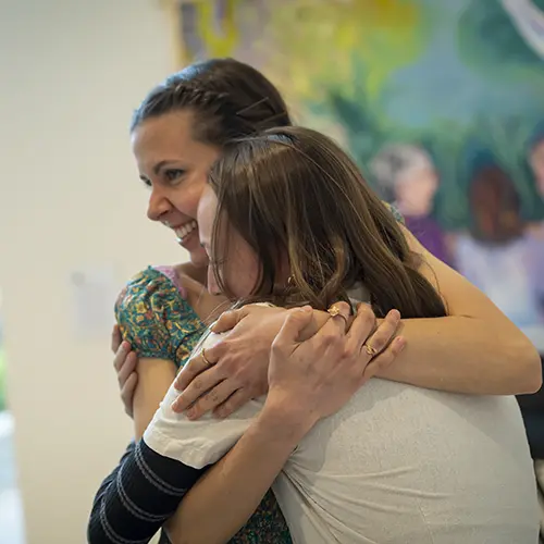 two people hugging at an art show.