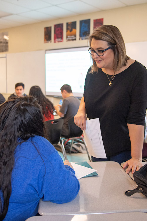 McMinnville High School teacher speaking with a student in a classroom.