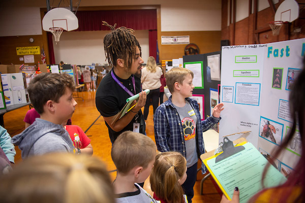 Linfield student judging a project at a McMinnville School District STEM fair.