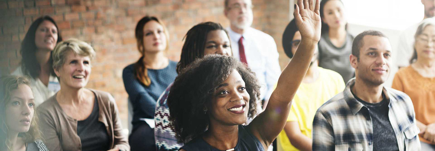 students in a classroom setting, one raising her hand