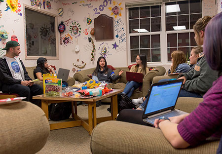 a group of students studying together in the SOAN departments with the graffiti wall behind them