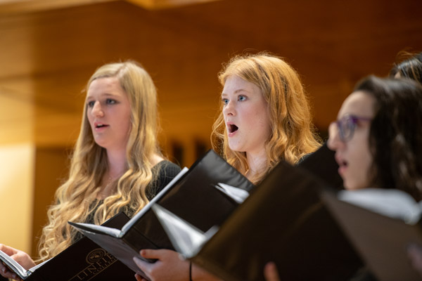 Three members of Cascara Voce performing on stage.