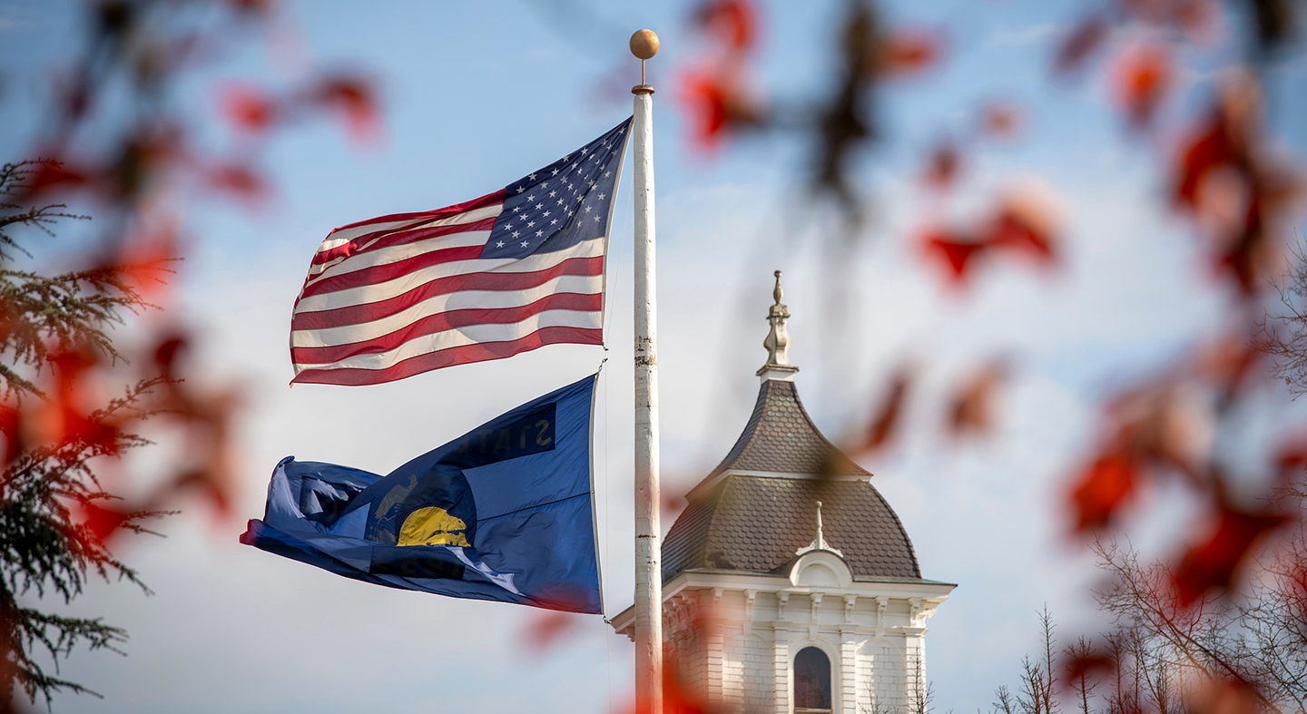 US and Oregon flag flying in front of Pioneer Hall